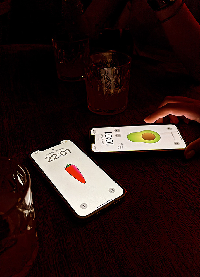 Deux téléphones sur une table avec des fonds d'écran affichant des illustrations de légumes du jeu de cartes Le Rush